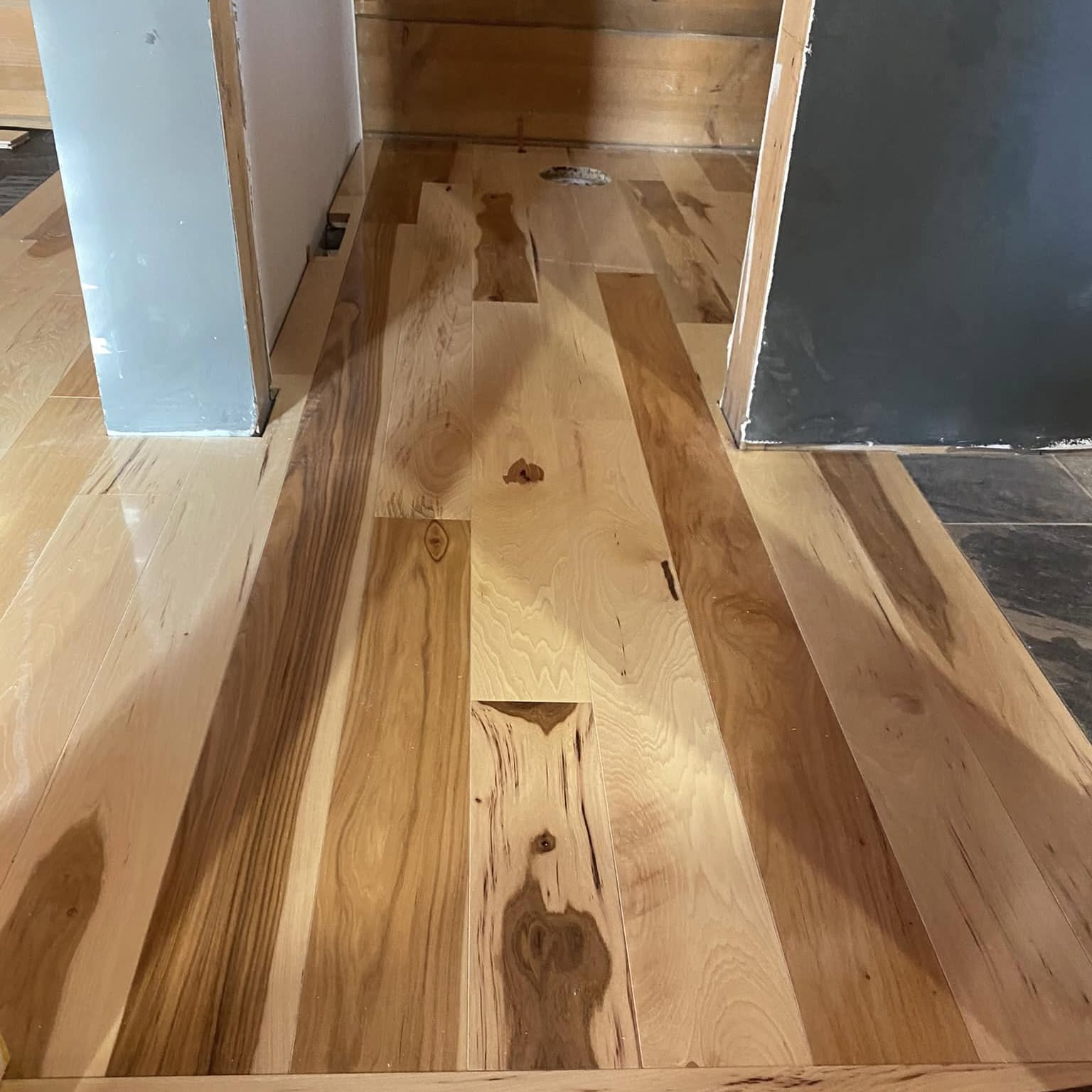 Natural hickory flooring being installed through a doorway
