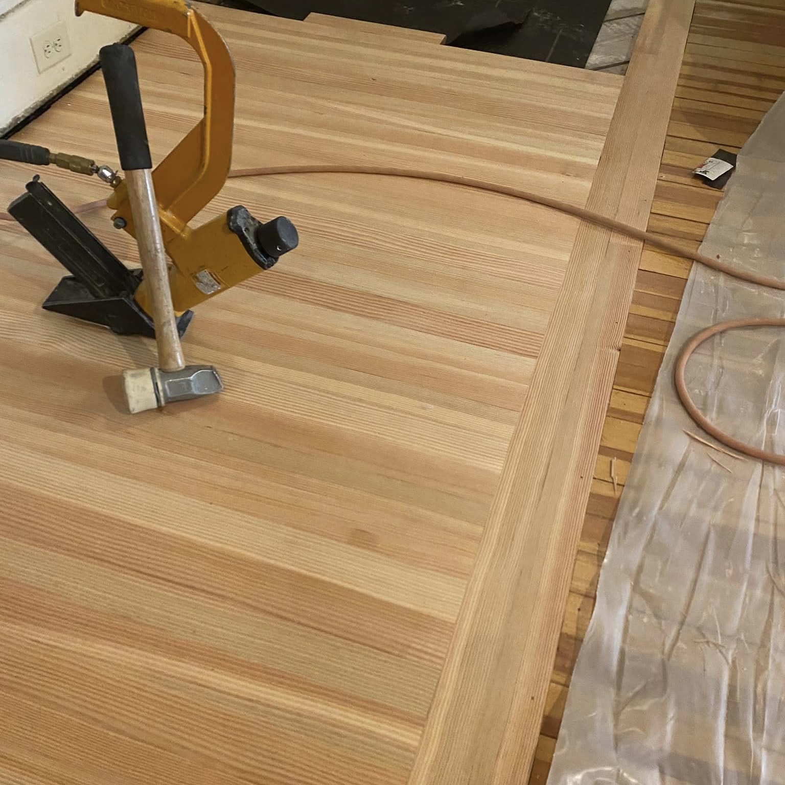 Fir flooring being nailed down with a flooring nailer over an existing floor
